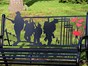 Remembrance Day black and red metal bench showing 4 soilders and 6 poppies