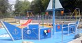 blue floored waterplay area with various sprinklers and water jets some forming a pirate ship shape