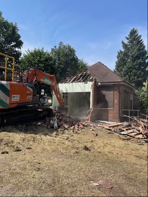 bulldozer demolishing old building in a local park