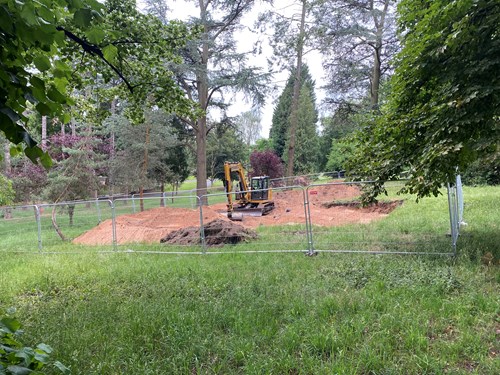 digger in fresh soil surrounded by fencing